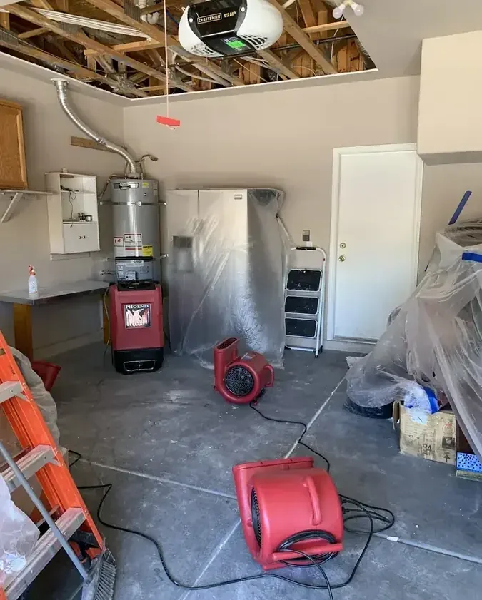 Air movers beside a water heater beneath an opened garage ceiling