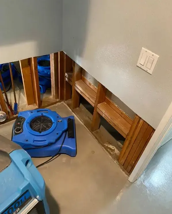 Air movers beside exposed wall studs and lower-wall openings