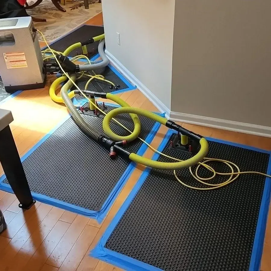 Floor drying mats secured with blue tape and connected to yellow hoses