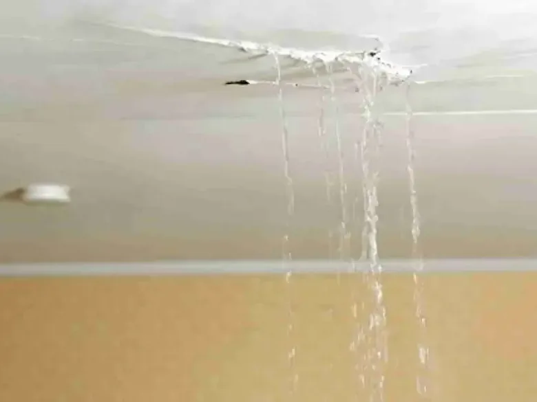 Water pouring through an opening in a damaged ceiling