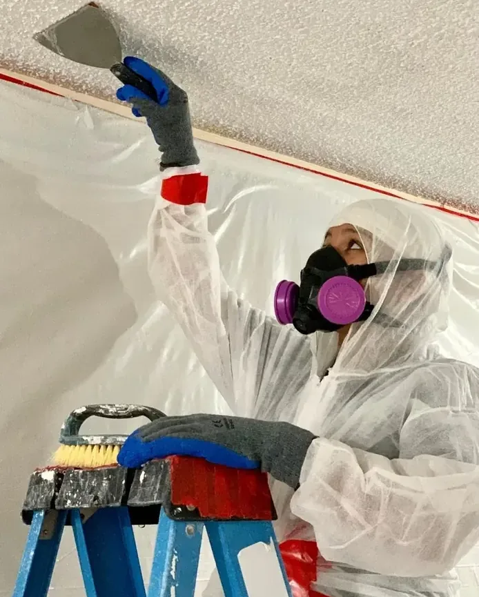 Worker removing damaged ceiling material inside a protected room